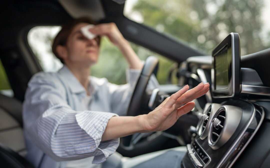 Woman drives car with broken air conditioning in hot Georgia summer weather. She wipes sweat off her forehead with a paper napkin.