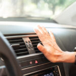 Woman holding her hand overtop A/C vent, checking to see if the air is warm or cold.
