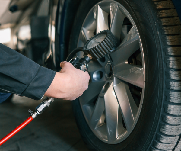 A mechanic checks tire pressure with a gauge during routine car maintenance in Downtown Atlanta, GA. Focus on the wheel and the instrument ensuring optimal vehicle safety and performance.