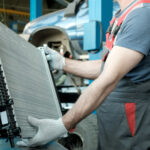 Mechanic inspects radiator on vehicle in auto shop.