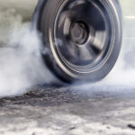 BMW racing car burning tire at starting line in race track