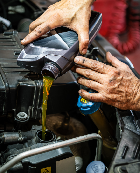 Mechanic in Norcross, GA pours fresh engine oil into a car engine for routine auto service