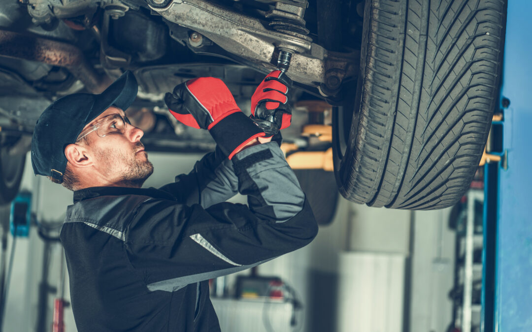 Mechanic upgrading and adjusting suspension system for European vehicle using a large metal wrench.