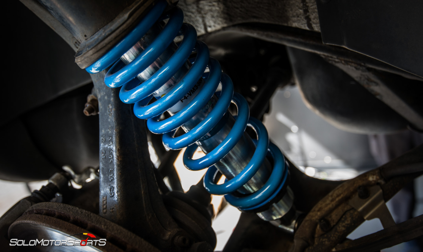 Close-up of blue aftermarket coilover spring on suspension strut — Solo Motorsports handling page
